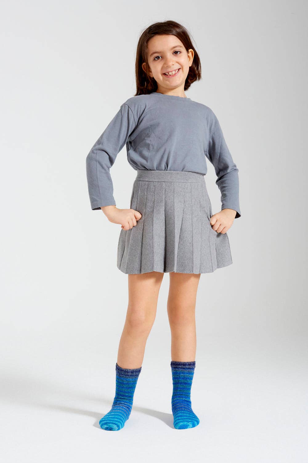 Child wearing blue and purple hand-knit socks made with Uneek Sock Kit Mini by Urth Yarns