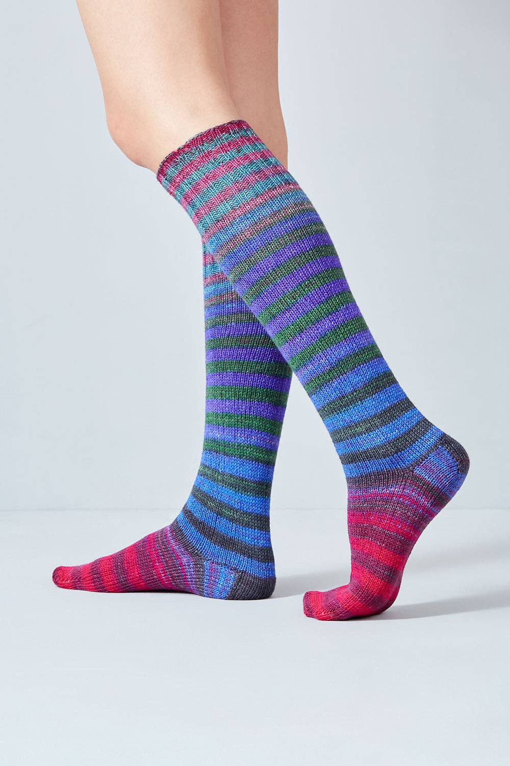 Colorful knee-high socks made from Urth Yarns Uneek Sock Kit featuring vibrant stripes
