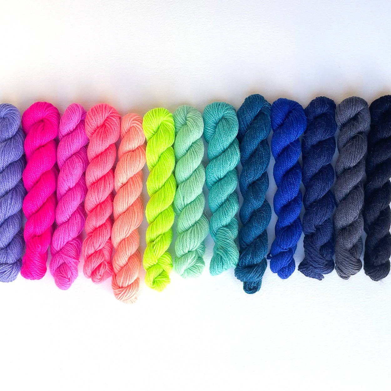 Colorful display of Kelbourne Woolens Perennial Minis yarn in vibrant shades for knitting and crocheting
