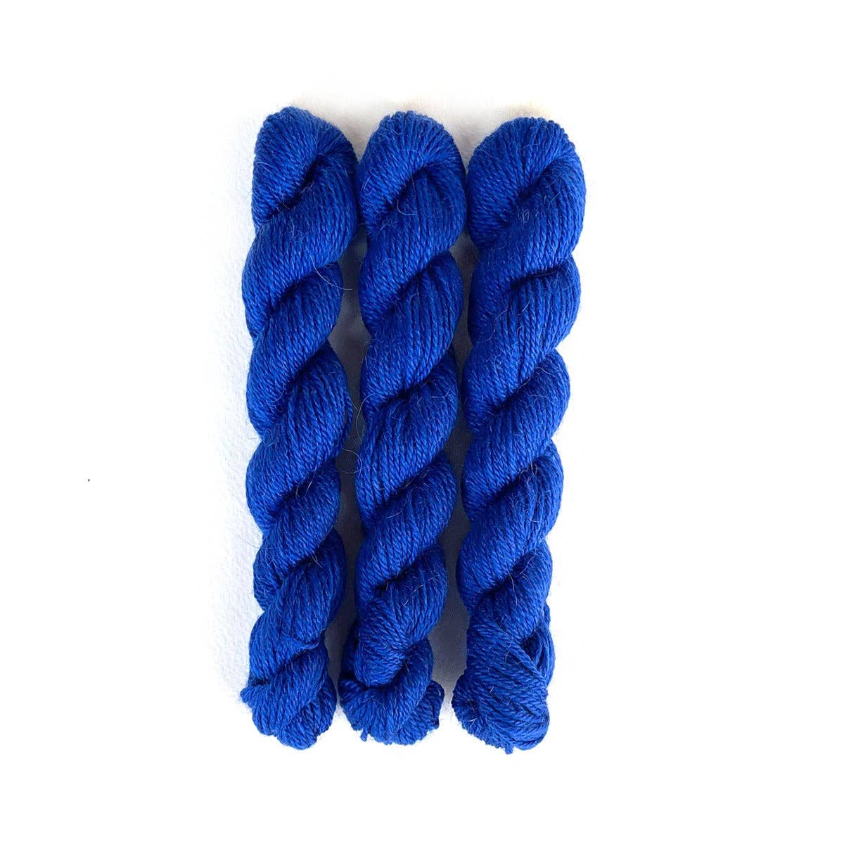 Three skeins of Kelbourne Woolens Perennial Minis yarn in vibrant blue for knitting and crocheting projects