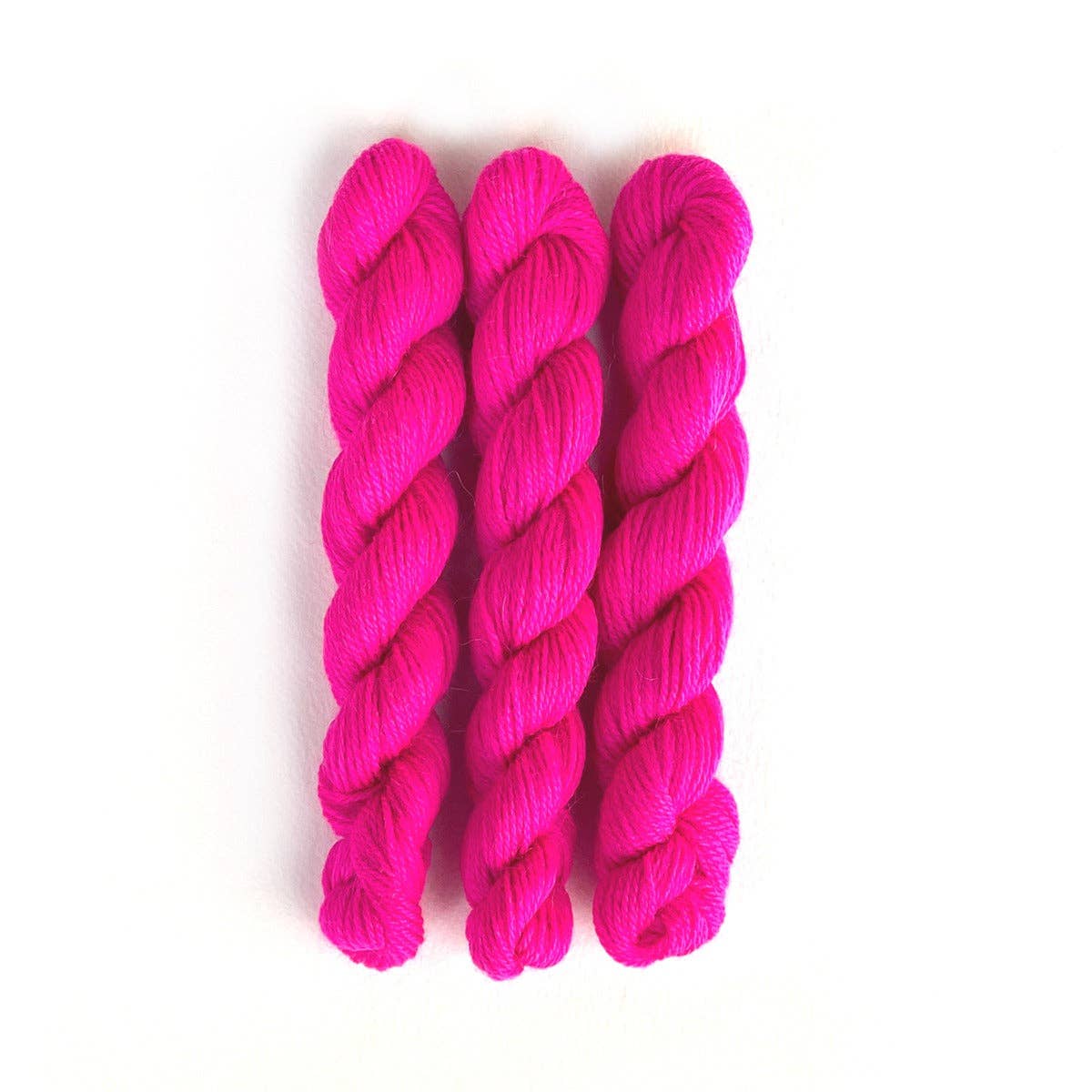 Four skeins of bright pink Perennial Minis yarn by Kelbourne Woolens for knitting and crafting