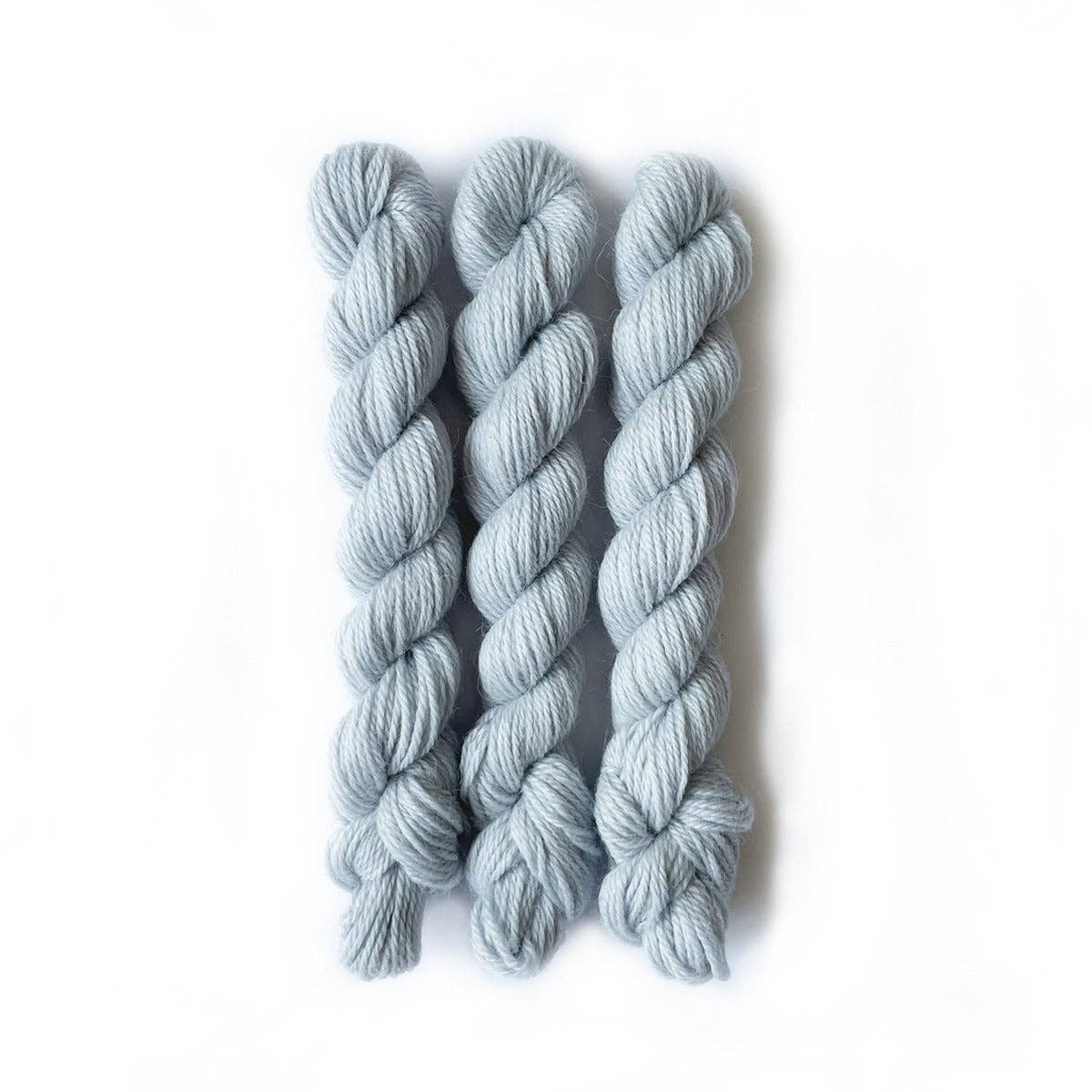 Three skeins of light blue Perennial Minis yarn from Kelbourne Woolens for knitting and crochet projects