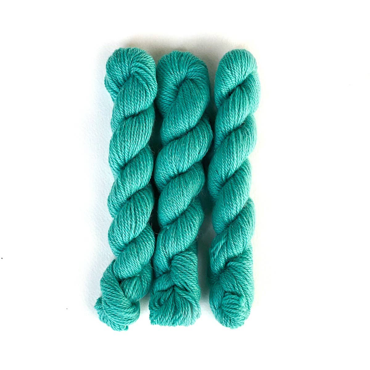 Three skeins of turquoise Perennial Minis yarn from Kelbourne Woolens for knitting and crafting