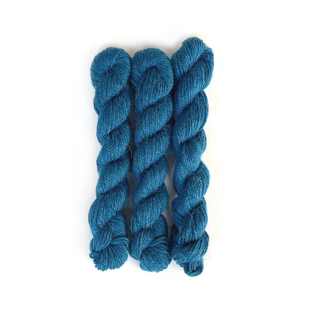 Kelbourne Woolens Perennial Minis yarn in teal color, featuring three twisted skeins for creative projects