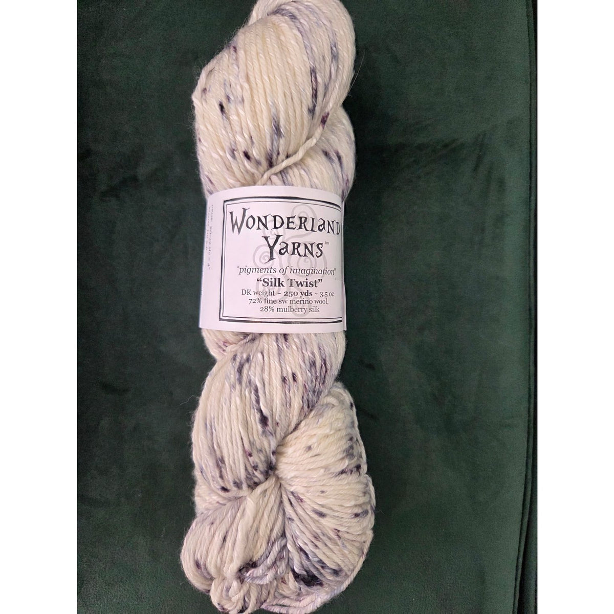 Wonderland Yarns Silk Twist skein in cream with purple flecks for knitting and crochet projects