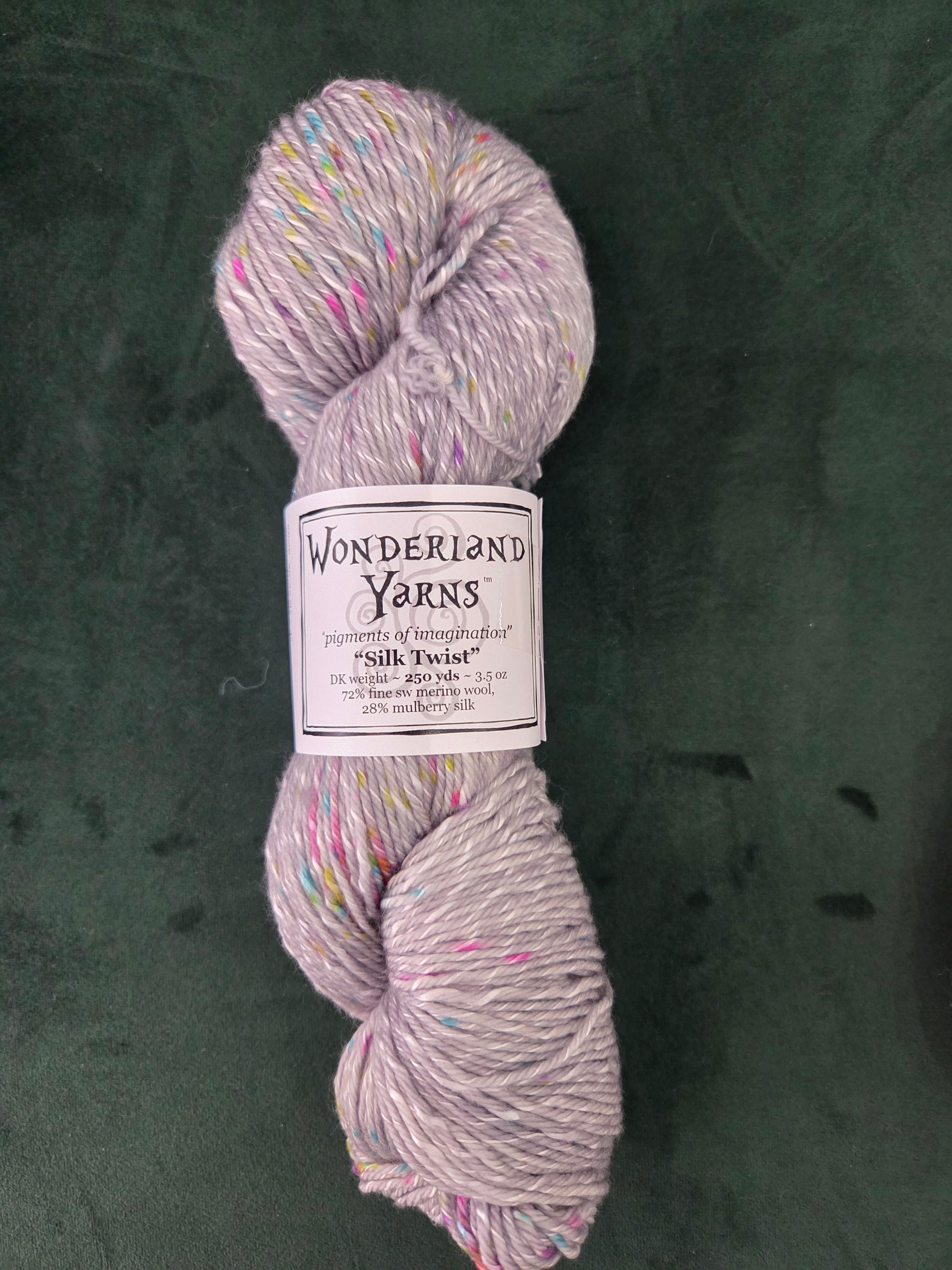 Frabjous Fibers light lavender tweed yarn skein with multicolored speckles on dark green backdrop Wonderland Yarns Silk Twist
