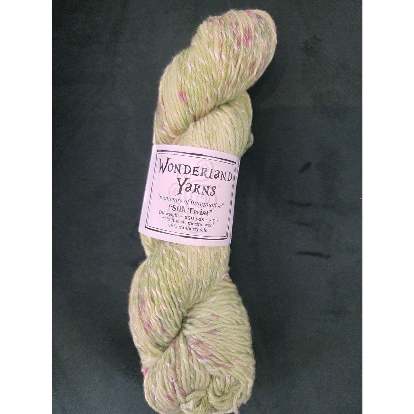 Frabjous Fibers skein of Wonderland Yarns Silk Twist light green yarn with pink speckles and label