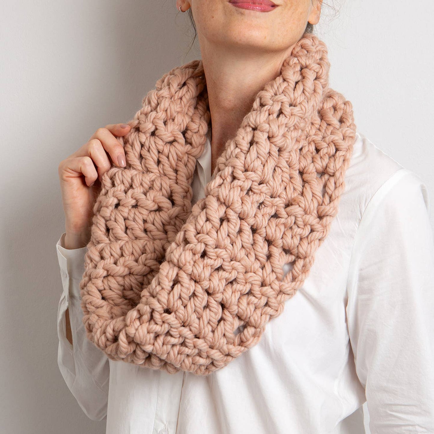 Woman wearing chunky blush pink infinity cowl made from Wool Couture Company beginner crochet cowl kit