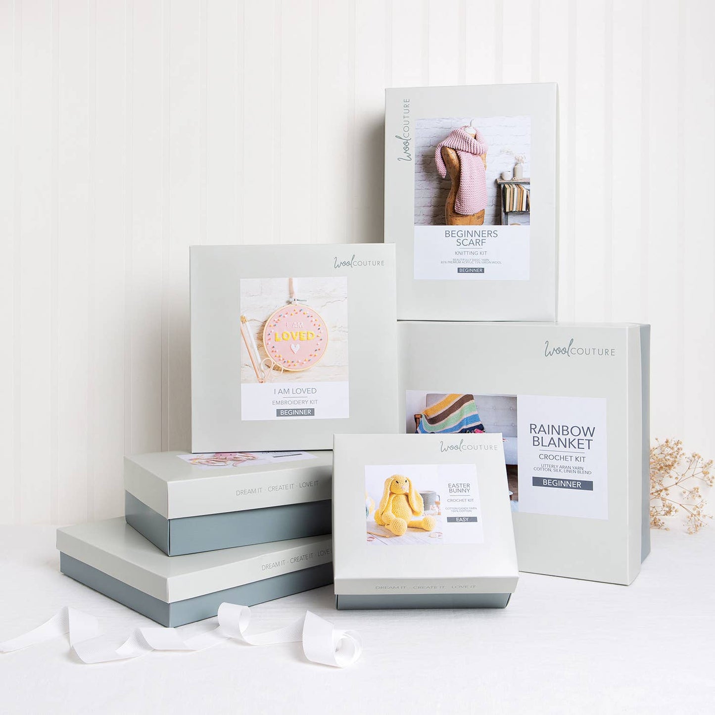 Wool Couture boxed knitting and crochet kits stacked on table including striped baby hat knitting pattern