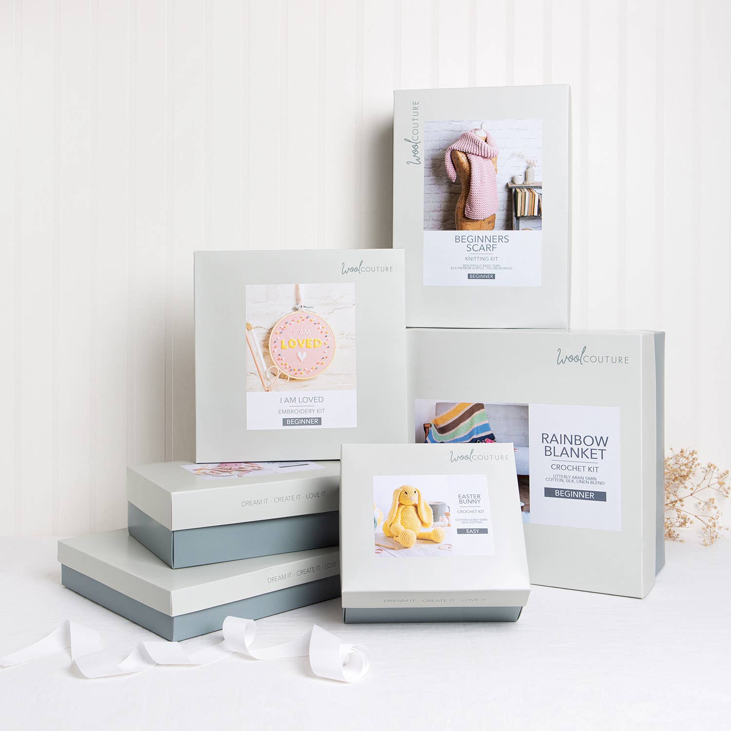 Wool Couture boxed knitting and crochet kits stacked on table including striped baby hat knitting pattern