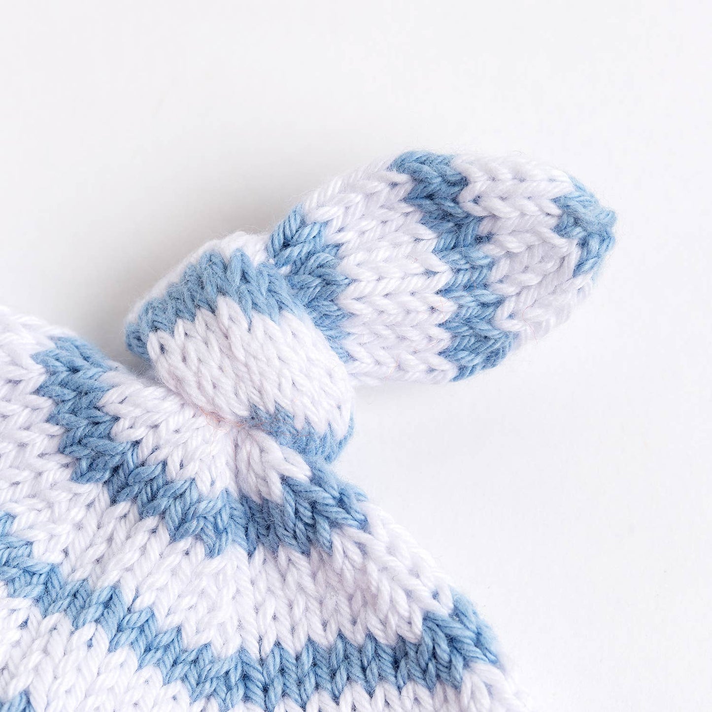Wool Couture Company striped baby hat knitting pattern showing soft white and blue striped newborn hat top with knot