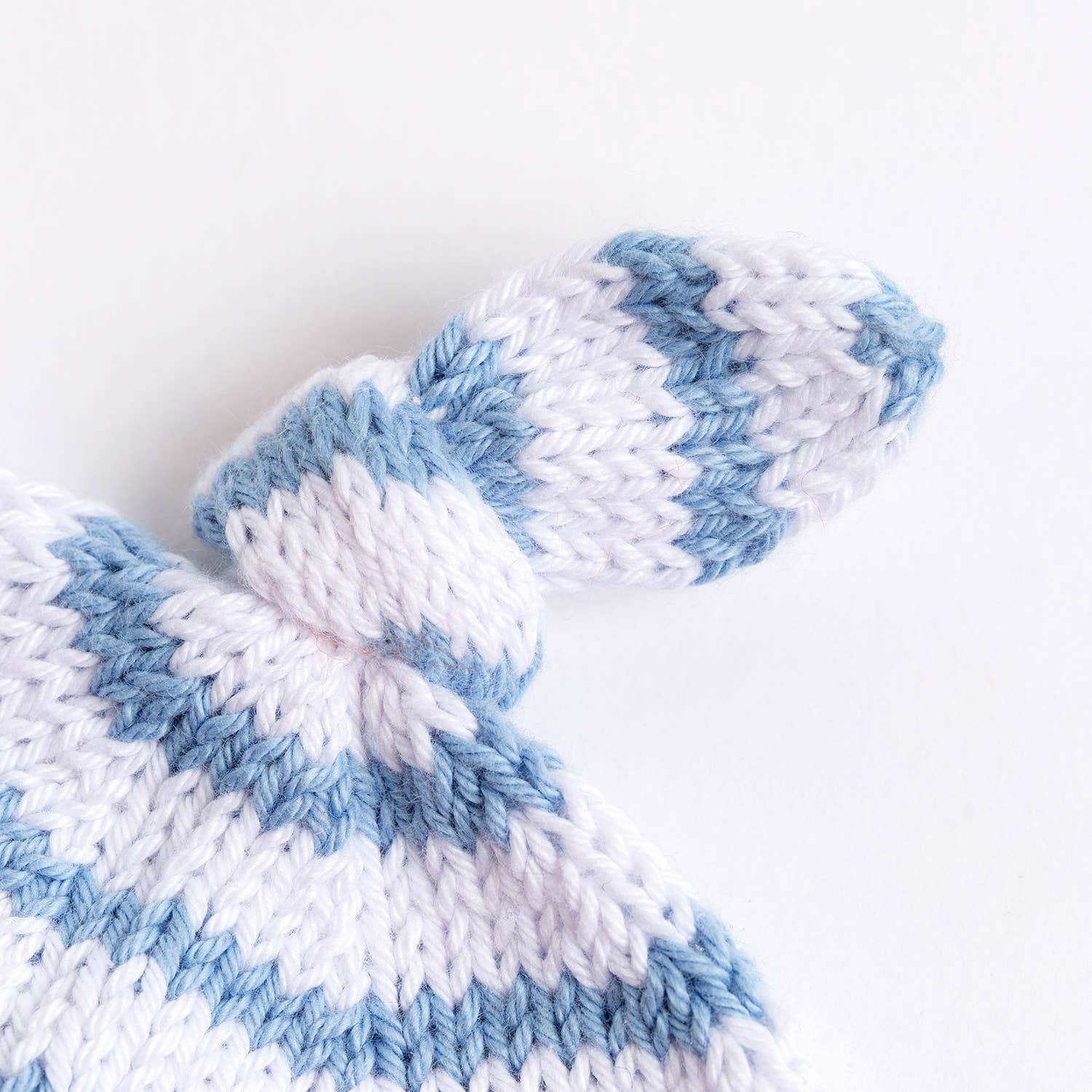 Wool Couture Company striped baby hat knitting pattern showing soft white and blue striped newborn hat top with knot