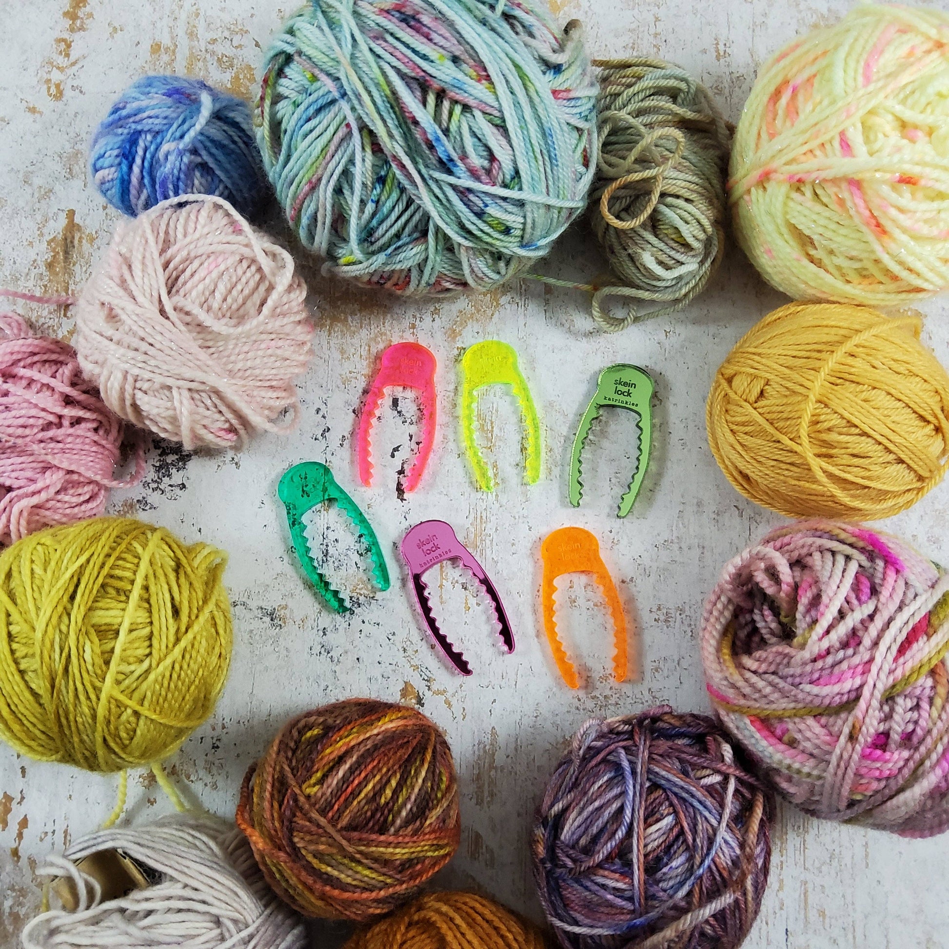 Colorful yarn spinning tool set surrounded by various skeins of yarn in different colors